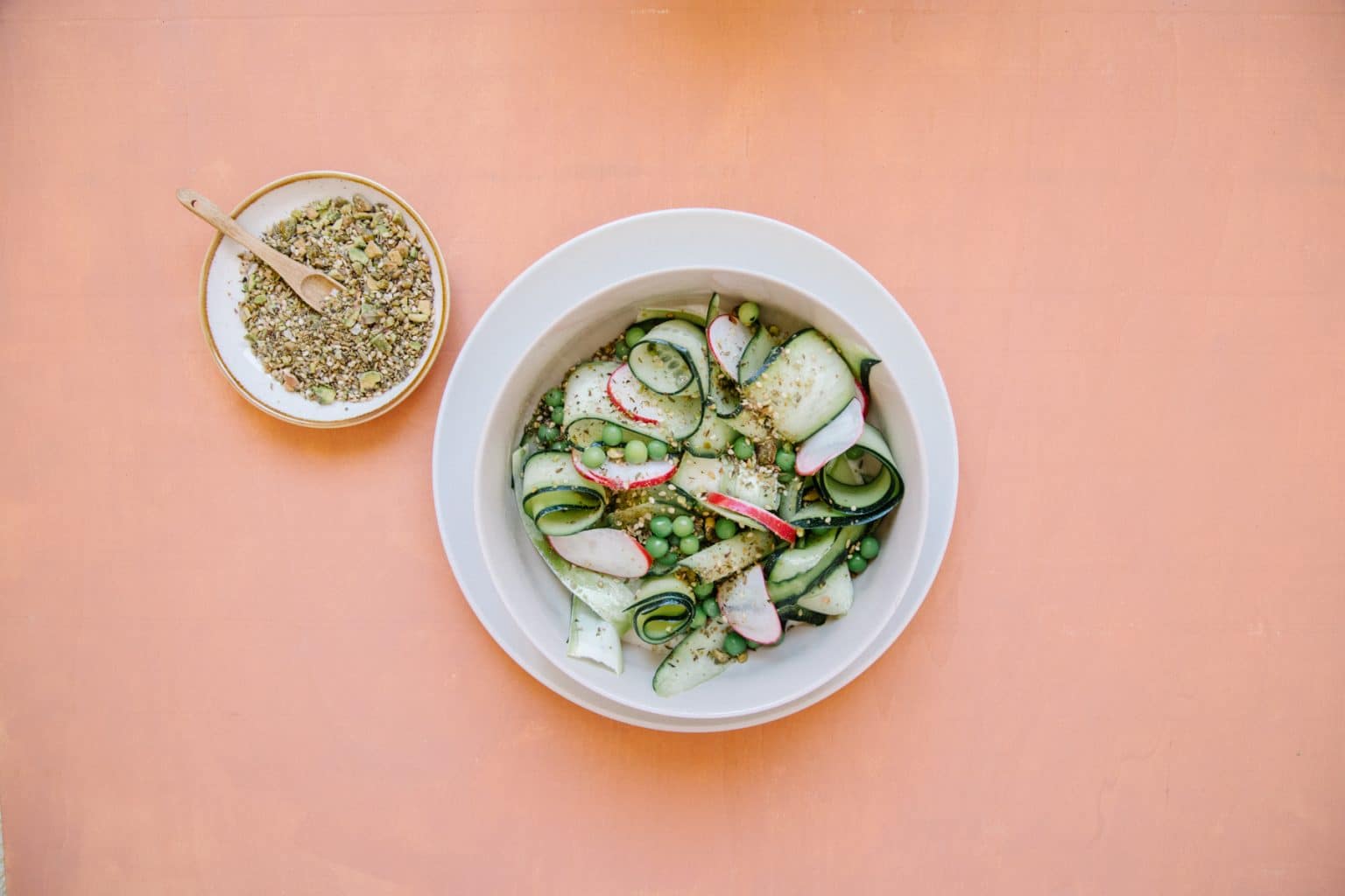 Frisse courgette-doperwt salade met romige witte bonenpuree, knapperige dukkah en citroenrasp